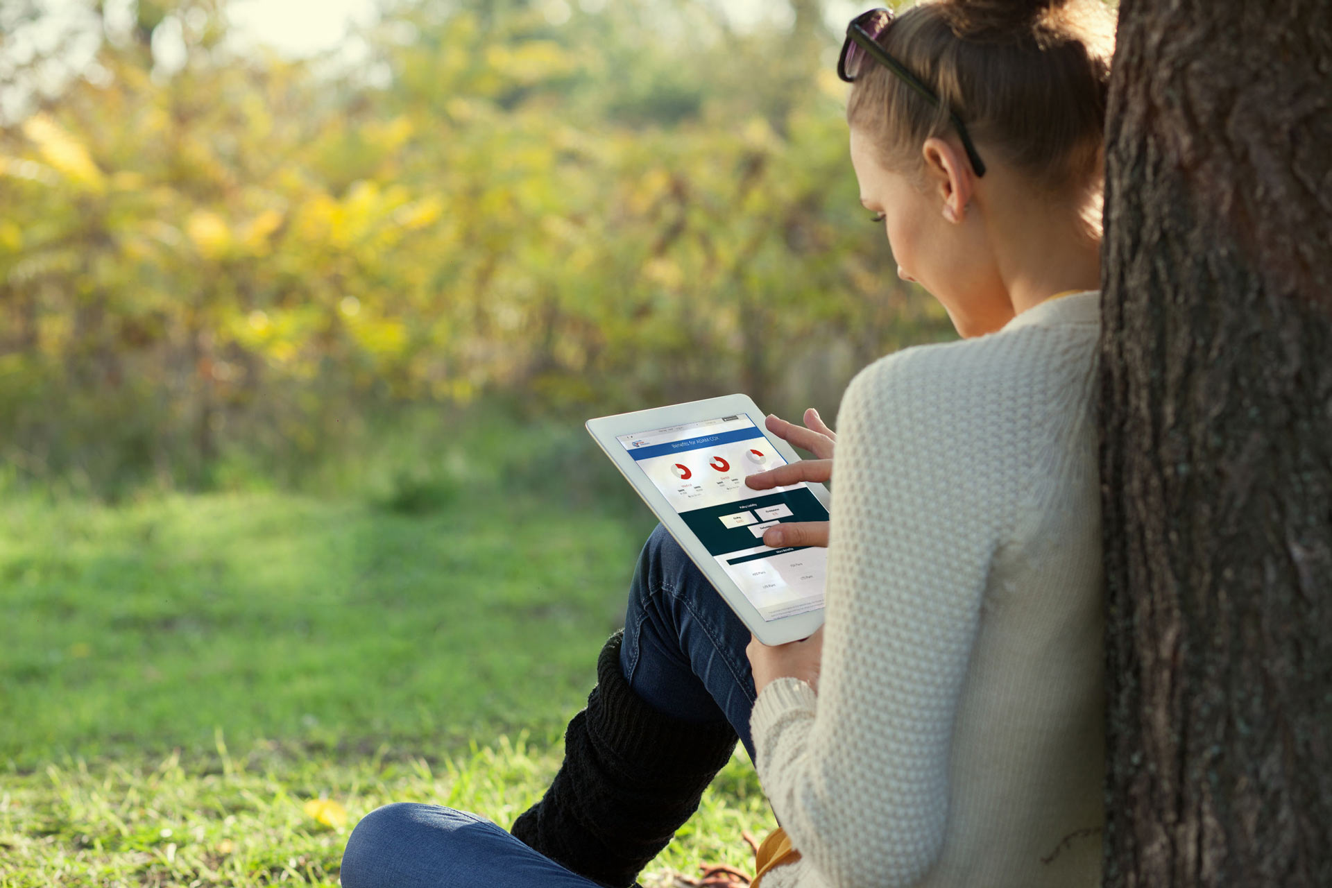 woman sitting under tree with iPad in-hands