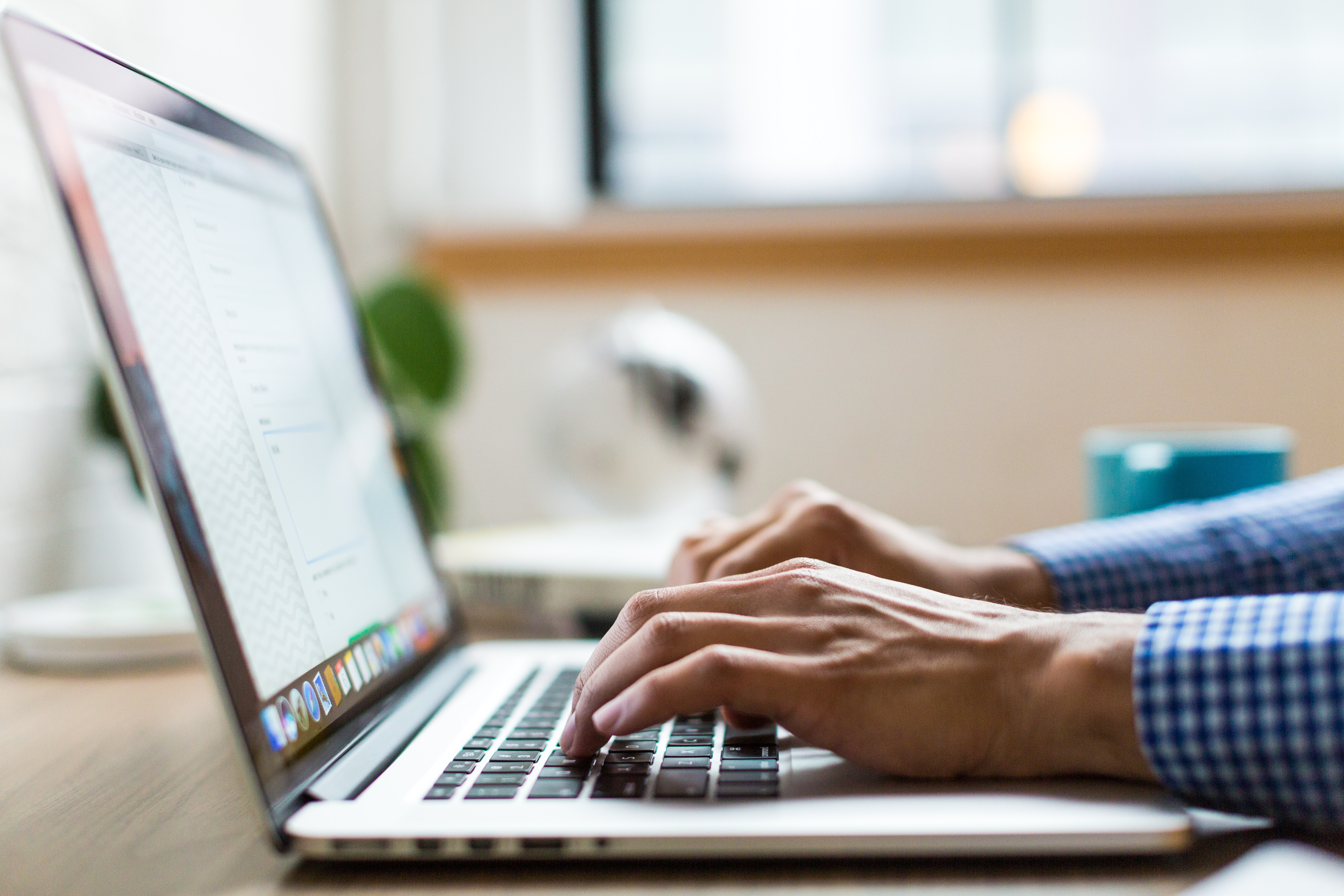 close up of hands typing on a laptop, in-office