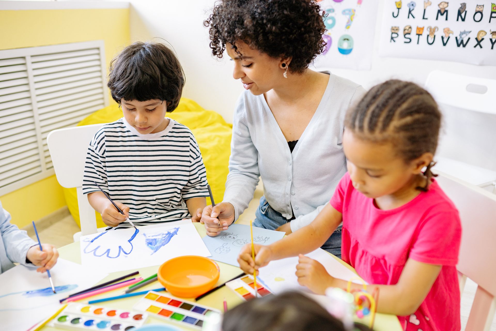 Woman assists children with art projects